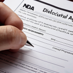 **

"Close-up of a hand signing a Non-Disclosure Agreement (NDA) with a pen, emphasizing the importance of protecting confidential information. Legal documents in the background, soft, professional lighting."

**